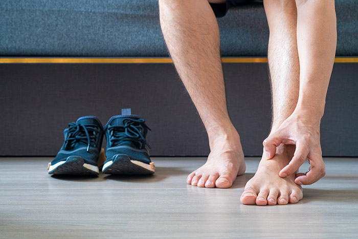 Man-itching-feet-trainers